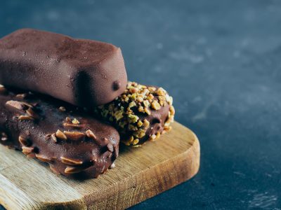Three kind of Eskimo ice cream in chocolate glaze on wooden board on blue background. Three kind of Eskimo ice cream in chocolate glaze on wooden board on blue background.